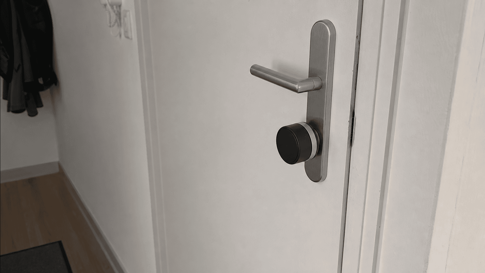 Nachrüstbares smartes Türschloss auf der Innenseite einer Wohnungstür, direkt am vorhandenen Schließzylinder unter dem Türgriff montiert